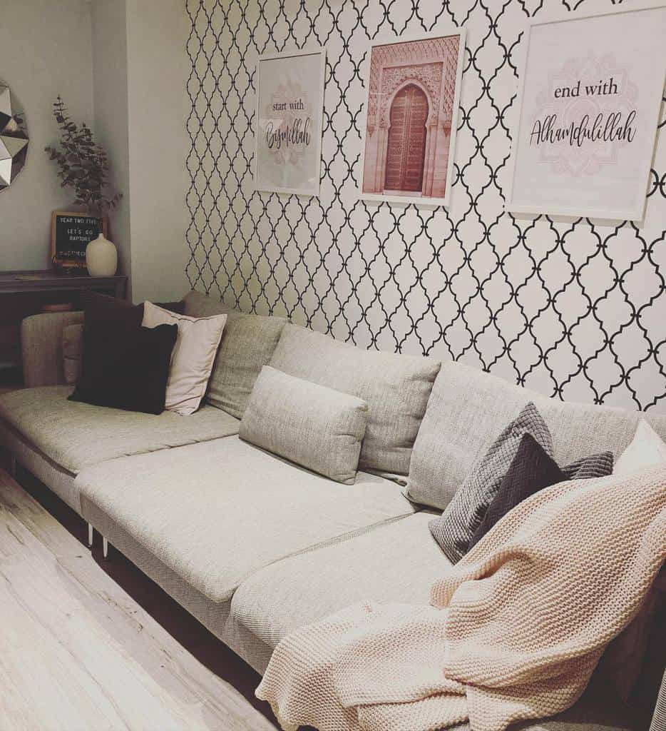 Modern living room with grey sectional, patterned wallpaper, and framed wall art.