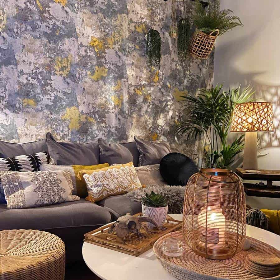 Cozy living room with a patterned wall, gray sofa, cushions, plants, and warm lighting from a woven lamp and candles