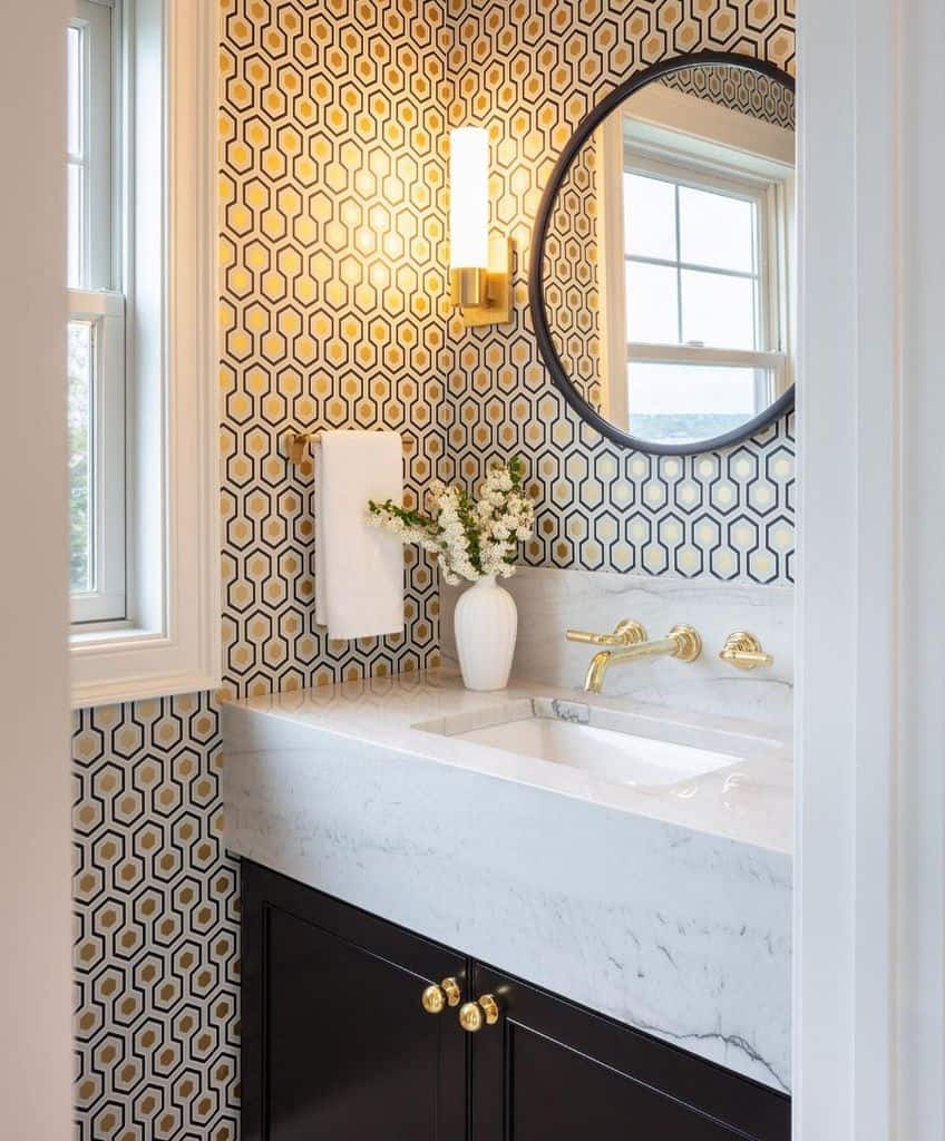 Modern bathroom with gold hexagon wallpaper, marble vanity, and black cabinets.