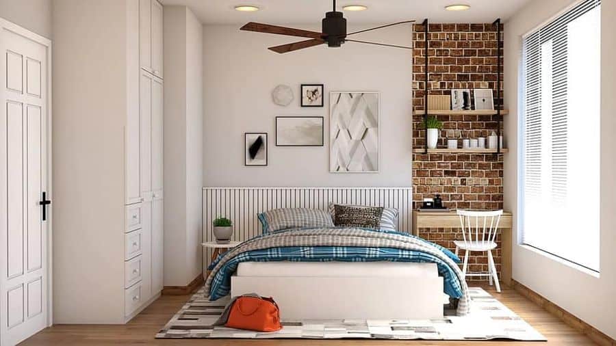 Modern bedroom with exposed brick wall, wooden desk, and ceiling fan.