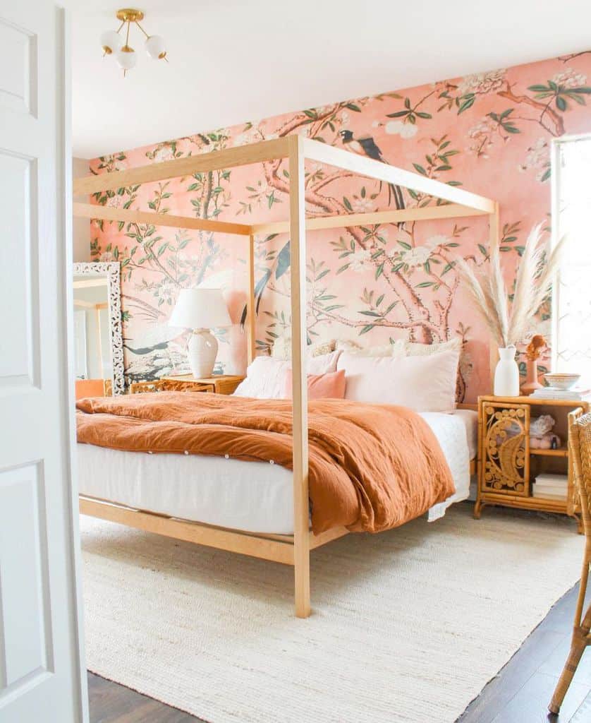 Bedroom with a wooden canopy bed, orange bedding, floral wallpaper, and rattan furniture