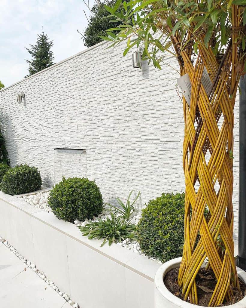 white stone wall water feature green bushes