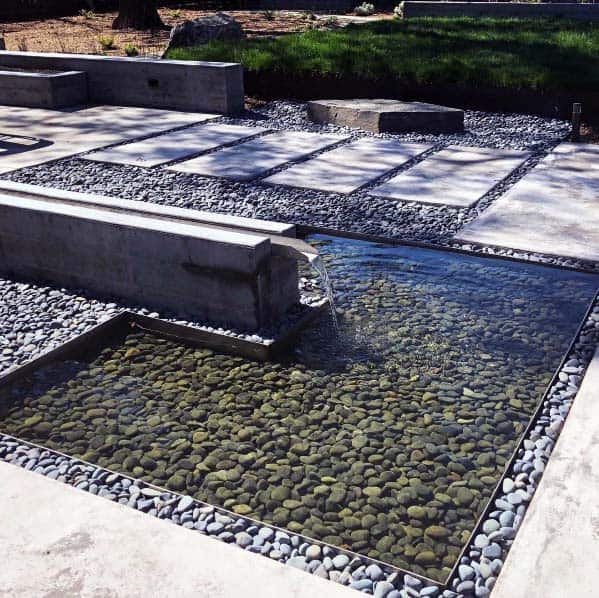 Contemporary water feature with river rocks, a sleek concrete fountain, and a serene water pool surrounded by stepping stones and gravel