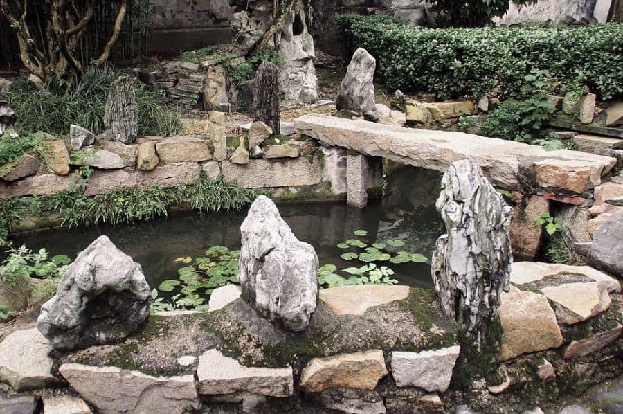 small backyard pond with rock bench seat lily pads 