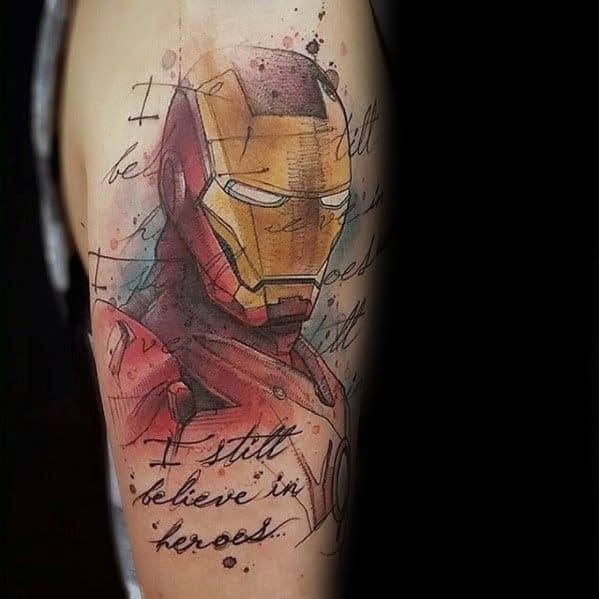 Iron Man tattoo featuring a vibrant portrait of his helmet, with splashes of color and the inspirational quote "I still believe in heroes" incorporated into the design for a powerful message.