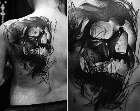 Abstract black and grey skull tattoo with chaotic sketch lines and bold shading, creating a raw, expressive, painterly effect on the back.