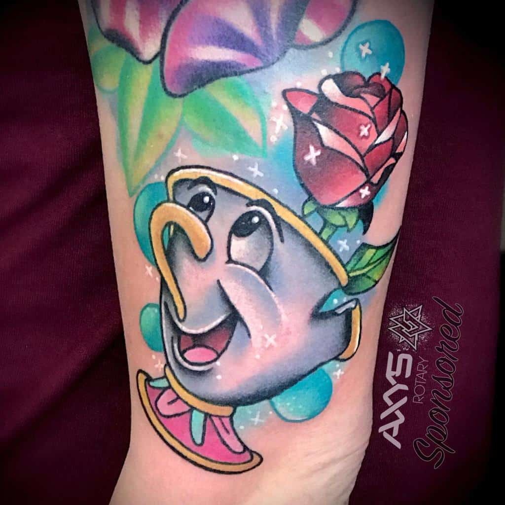 A colorful tattoo of Chip from Beauty and the Beast with a rose and sparkles in the background, featuring vibrant watercolor effects