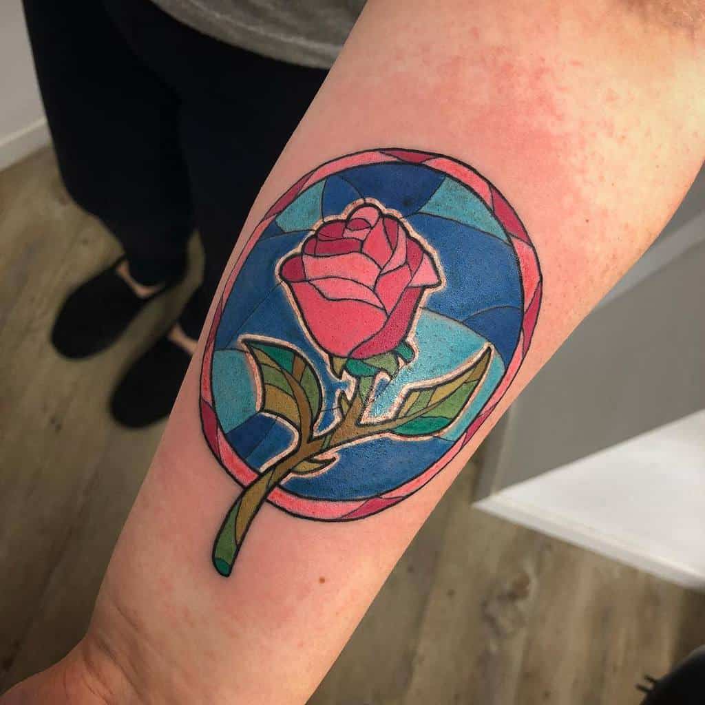 Tattoo of a red rose with a blue stained glass background on arm