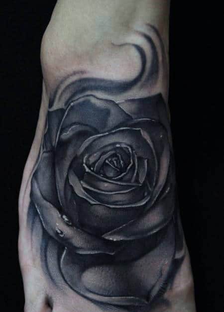 Black and gray rose tattoo with abstract swirls on skin