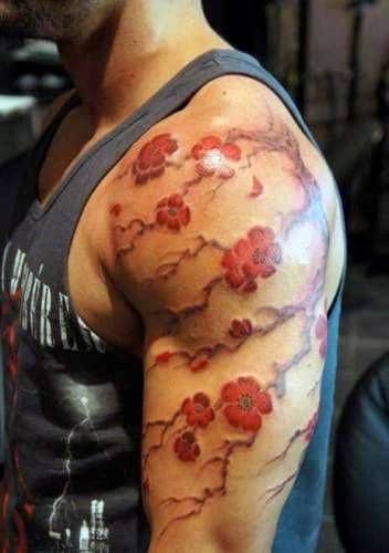 Watercolor-style cherry blossom tattoo on the upper arm, featuring delicate red flowers and soft flowing branches for an artistic look