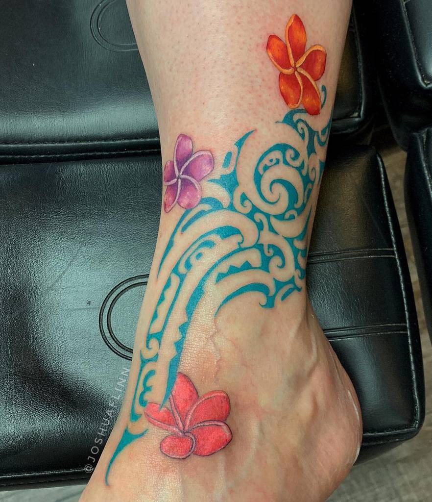Vibrant tattoo features colorful Plumeria flowers in shades of red, orange, and purple, intertwined with intricate blue tribal patterns, creating a bold and artistic design