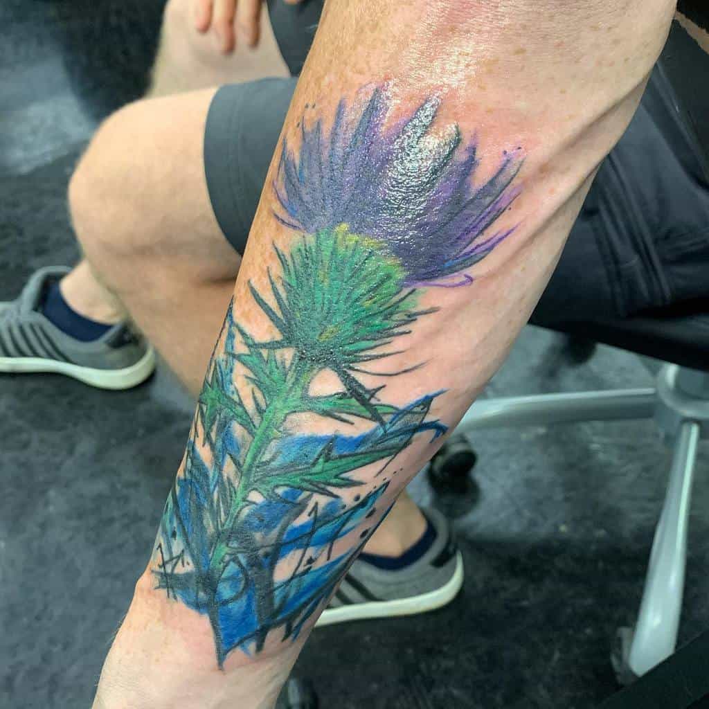 A colorful thistle tattoo on a man's forearm