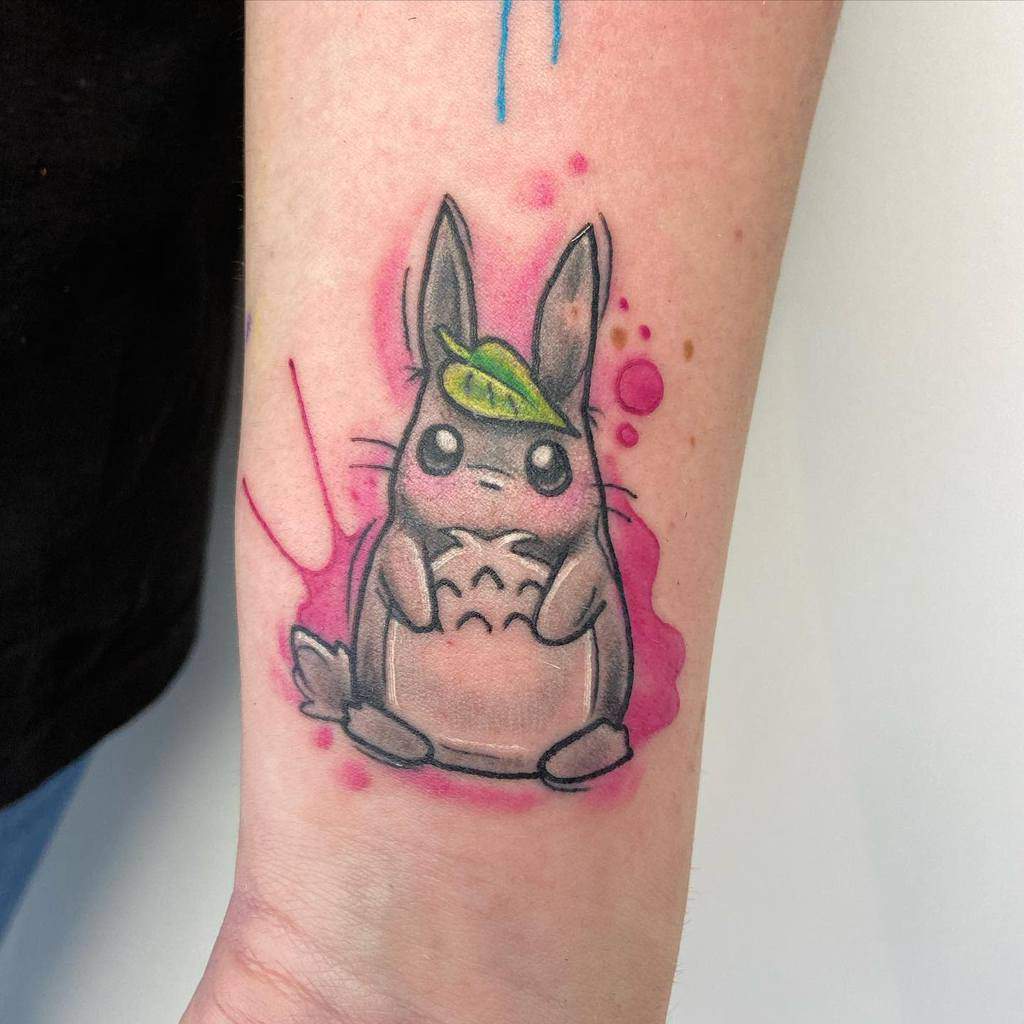 Tattoo of a cartoon rabbit with a leaf on its head on a person's forearm