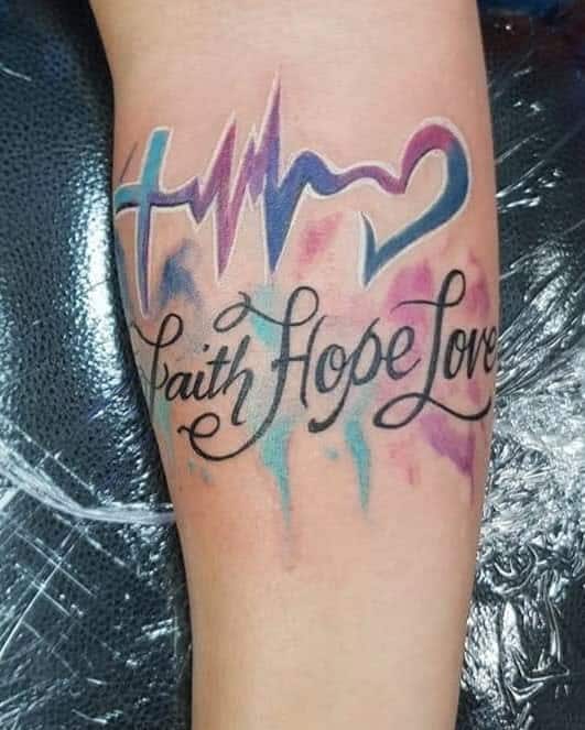 Colorful tattoo with a cross, heartbeat, heart, and the words "Faith Hope Love" on a forearm