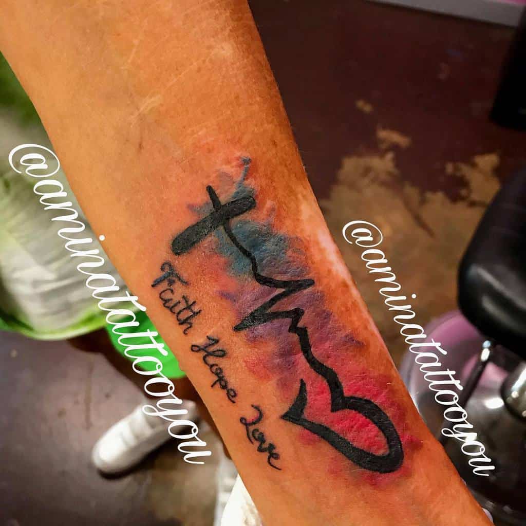 Forearm tattoo with a cross, heartbeat line, and heart, reading "Faith Hope Love," with colorful background