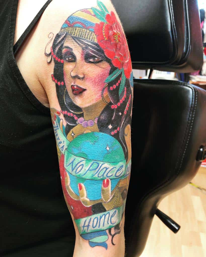 Tattoo of a gypsy woman with colorful headscarf and flower, holding a globe with text