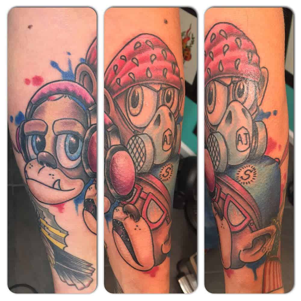 Colorful tattoo of three cartoon-style monkeys representing 'Hear No Evil, See No Evil, Speak No Evil,' with vibrant splashes of red and blue