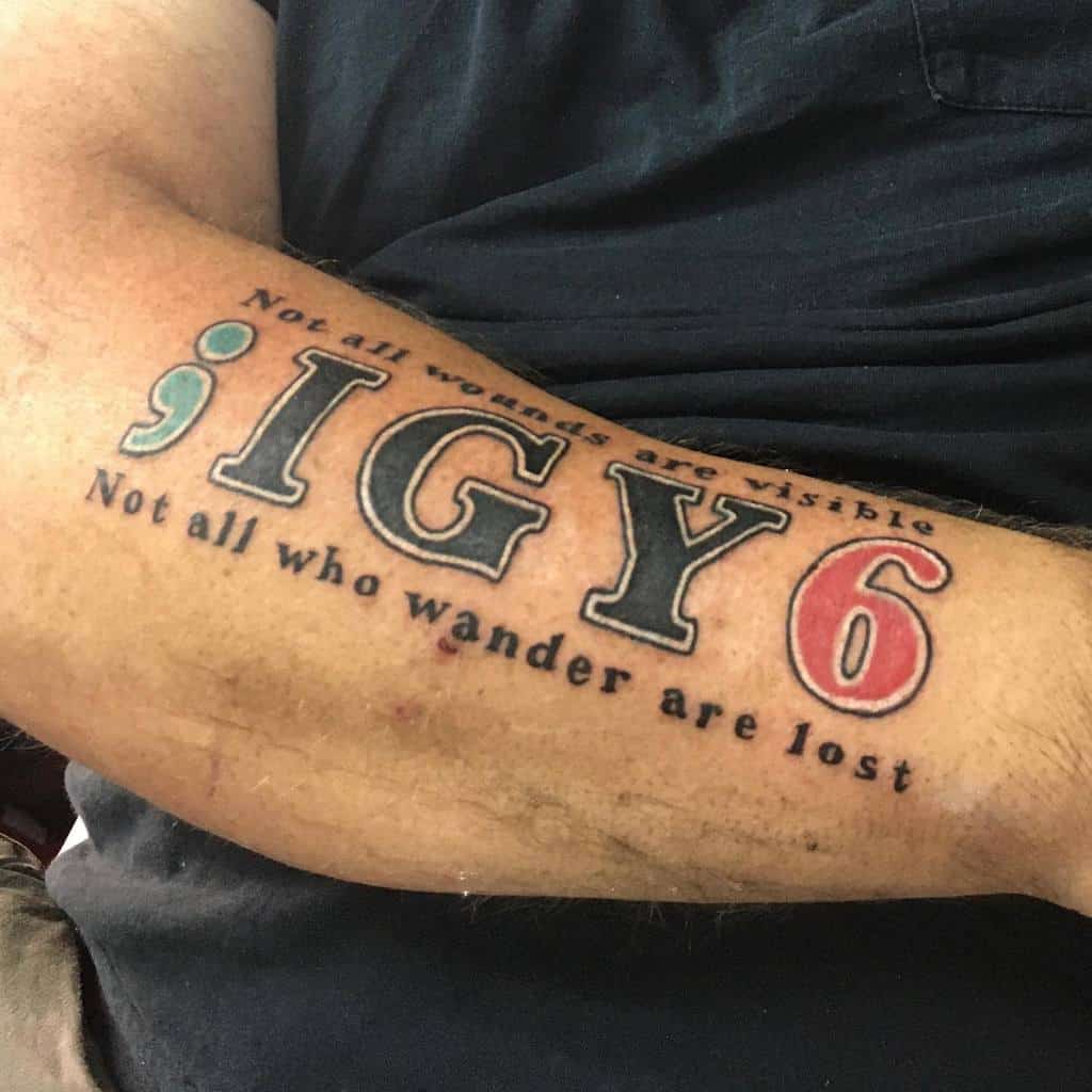 Tattoo on an arm reads: ";IGY6" with "Not all wounds are visible. Not all who wander are lost" above and below the text