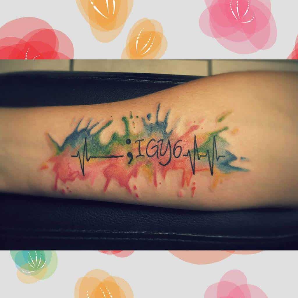 Forearm tattoo with colorful splash and heartbeat line, featuring the text ";IGY6"