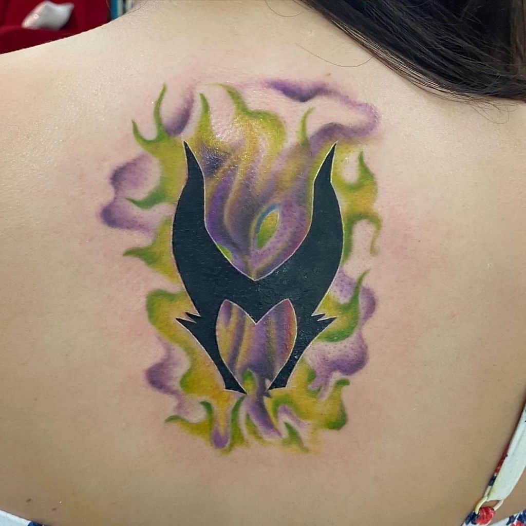 Minimalistic Maleficent silhouette tattoo surrounded by vibrant purple and green watercolor flames on the upper back