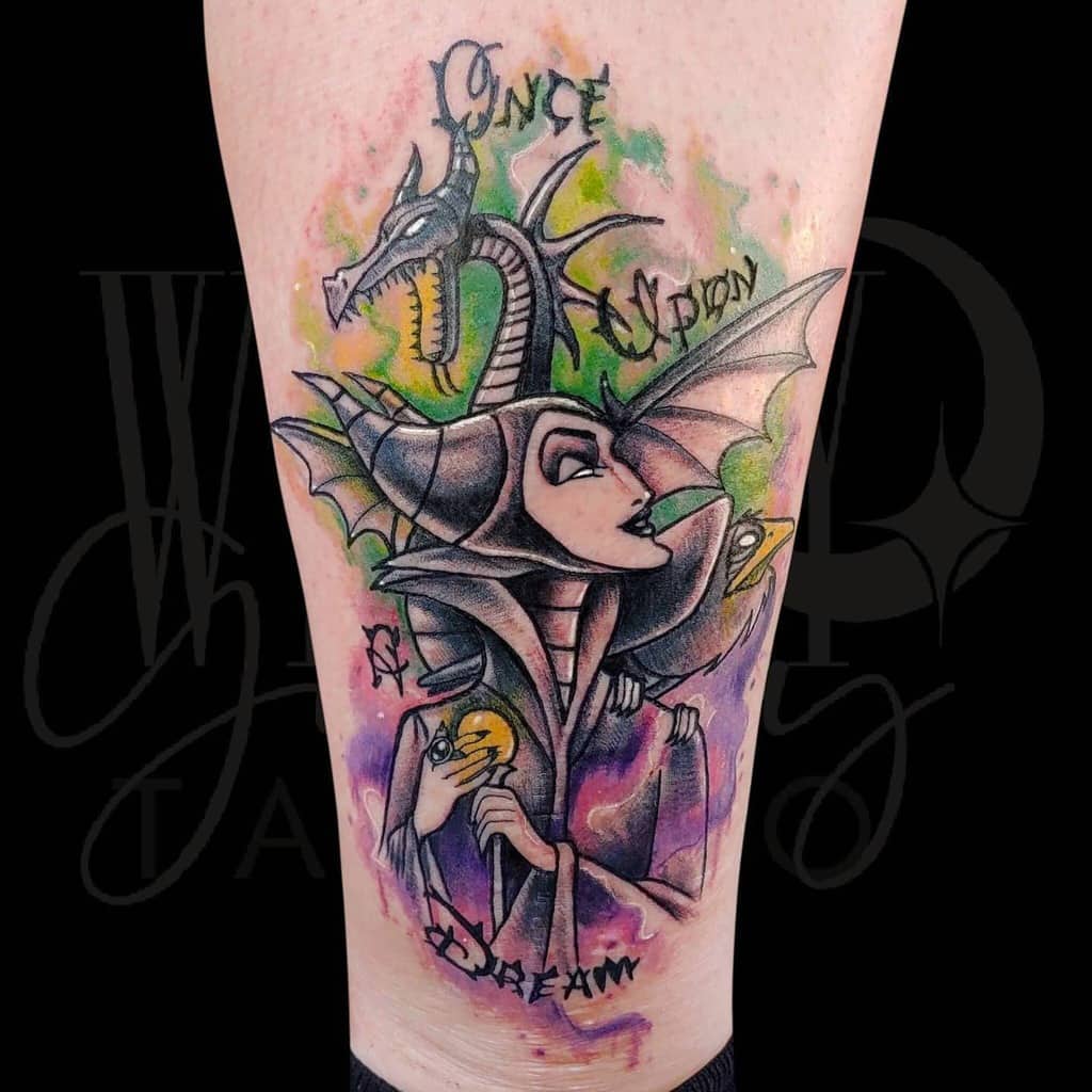 Vibrant watercolor-style tattoo of Maleficent with her dragon, featuring colorful hues and the text 'Once Upon a Dream,' blending fantasy and art