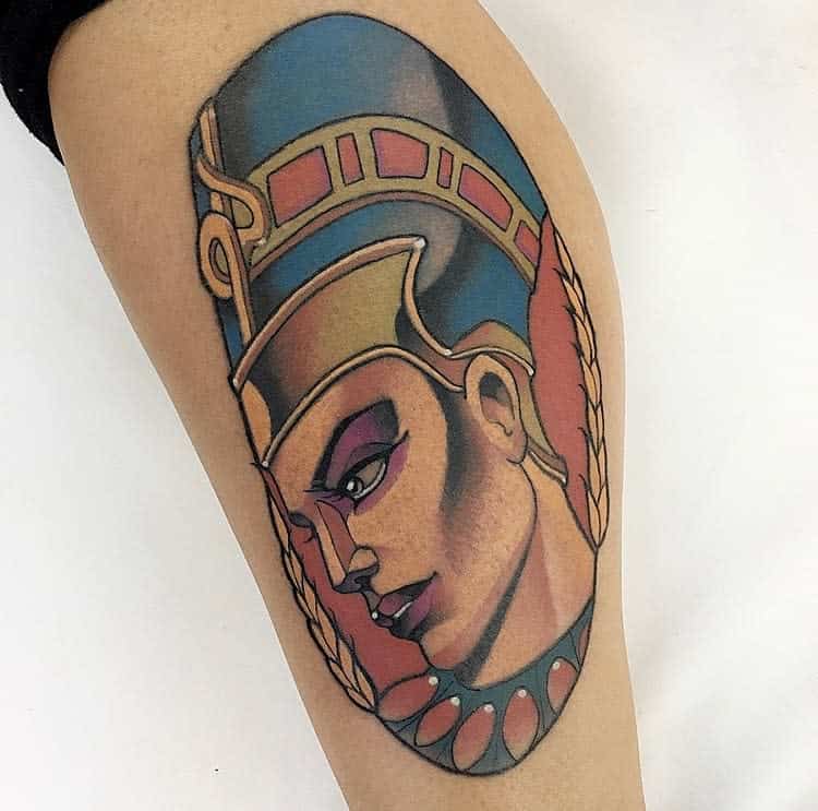 Tattoo of an ancient Egyptian queen with a headdress, featuring vibrant colors on an arm