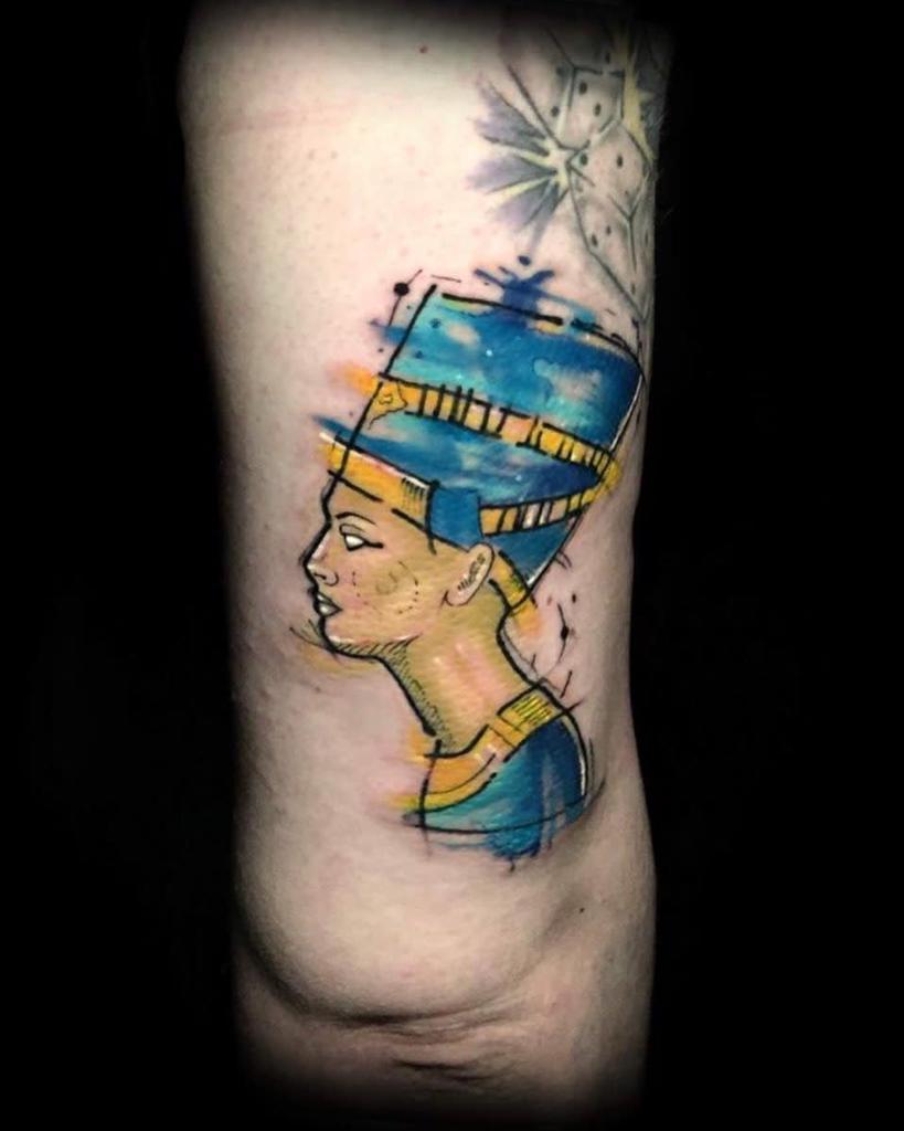 Colorful tattoo of an Egyptian queen in profile, with blue and yellow accents on arm