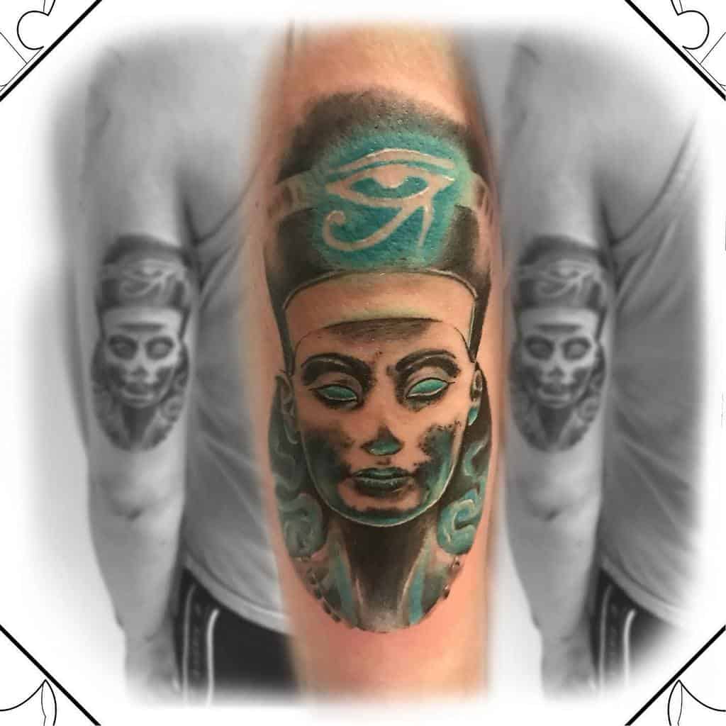 Tattoo of an Egyptian figure with turquoise accents and the Eye of Horus on an arm