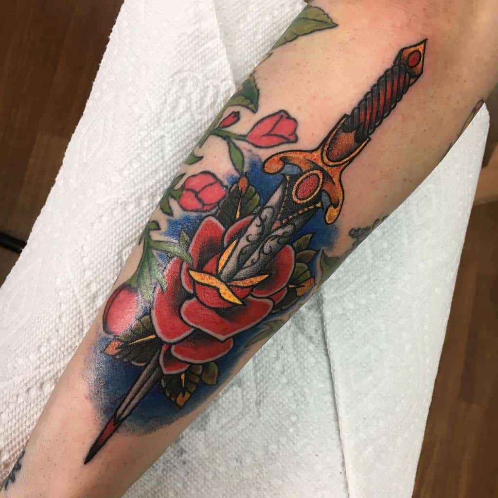 Tattoo of a sword piercing a red rose on an arm