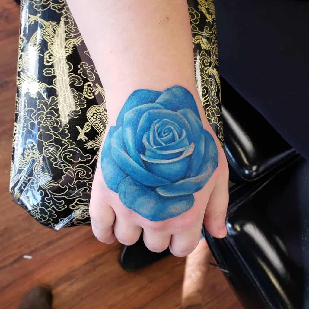 A blue rose tattoo on a person's hand