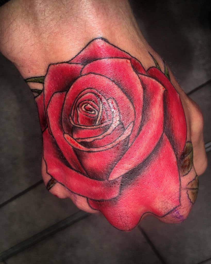 Red rose tattoo on the top of a hand, with detailed shading and outlines