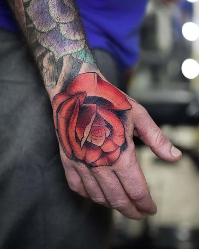 A vibrant red rose tattoo on a hand