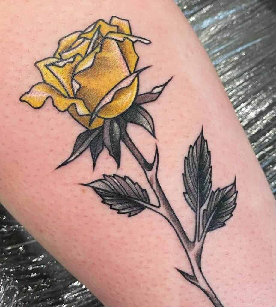 A tattoo of a yellow rose with green leaves and a black stem