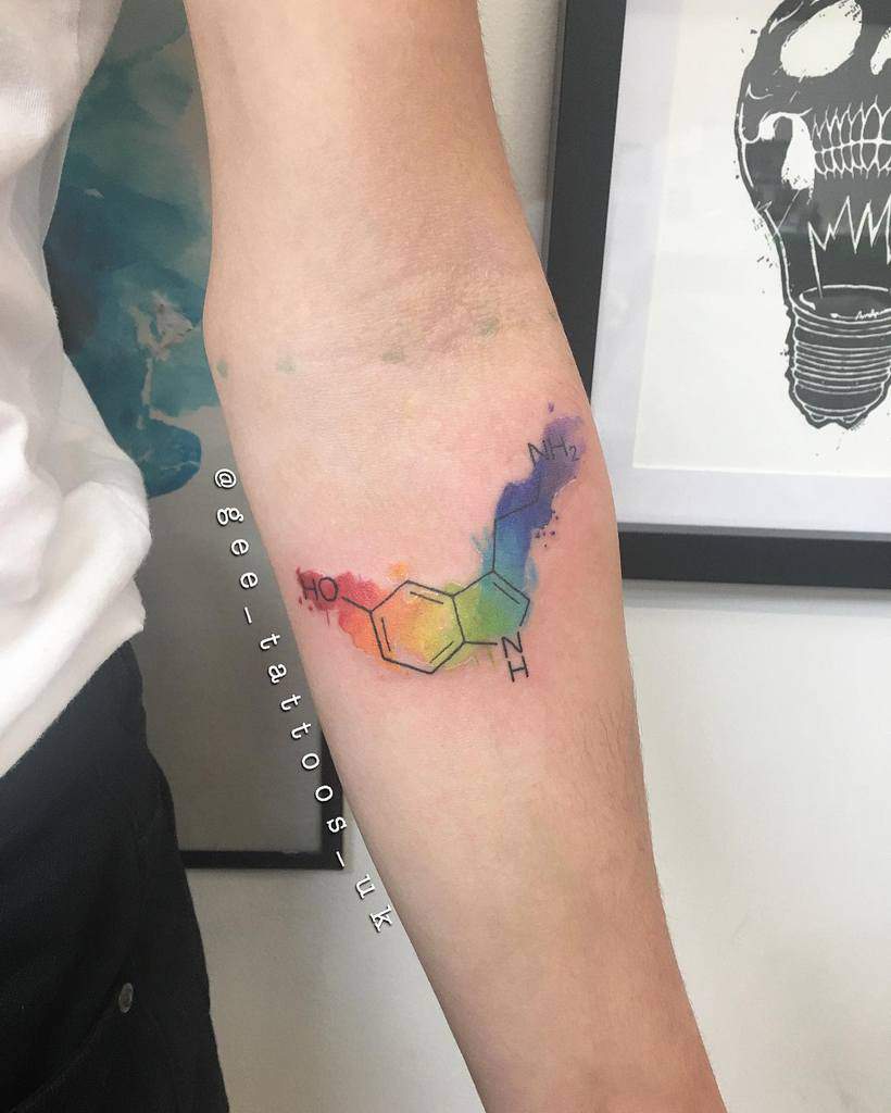Colorful serotonin molecule tattoo on forearm with watercolor splash background