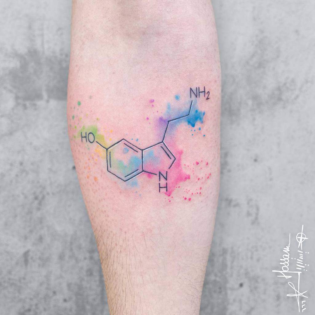 Tattoo of serotonin molecule with colorful watercolor background on a an arm