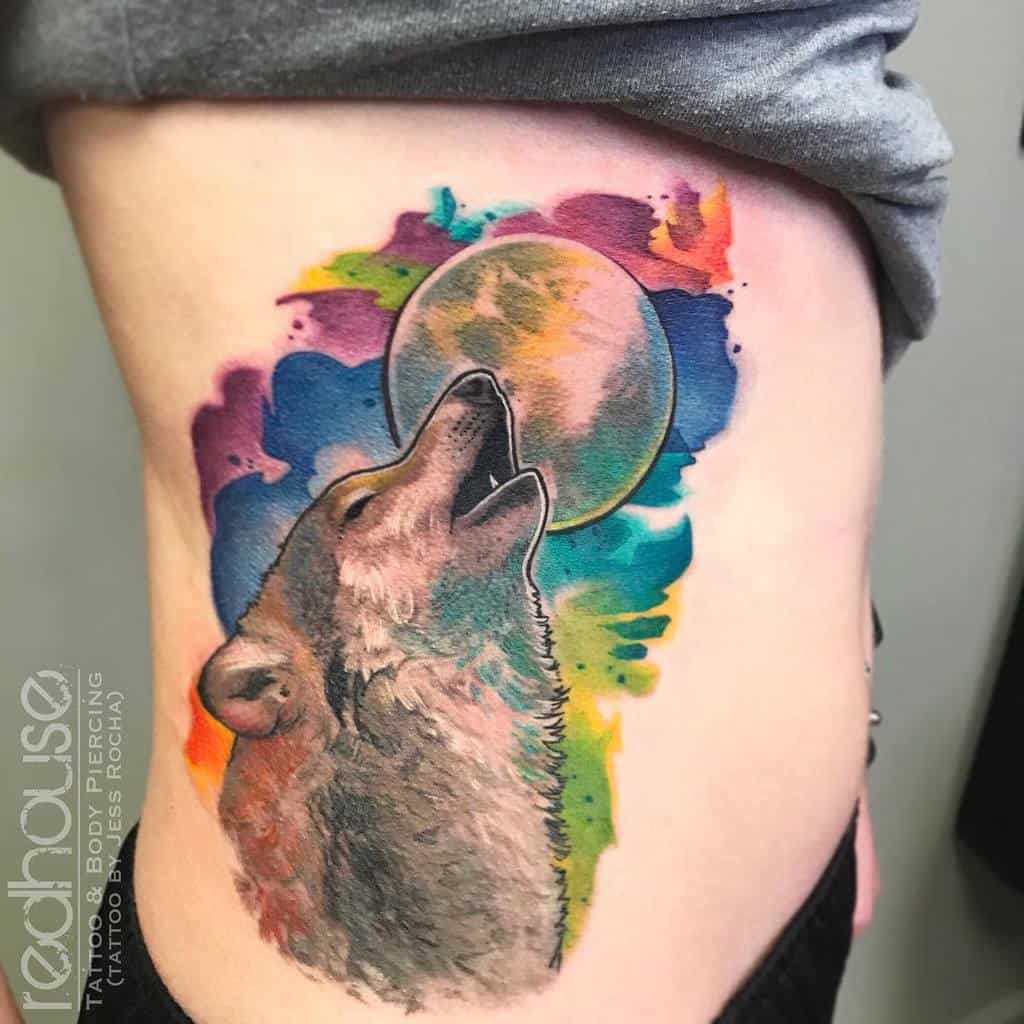 Colorful tattoo of a wolf howling at the moon against a vibrant, abstract background