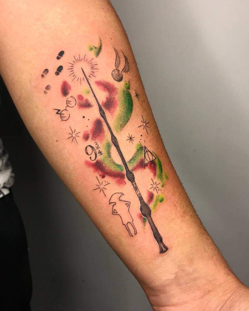 Magical forearm tattoo with a wand, footprints, glasses, and iconic symbols, accented by watercolor splashes in green and red