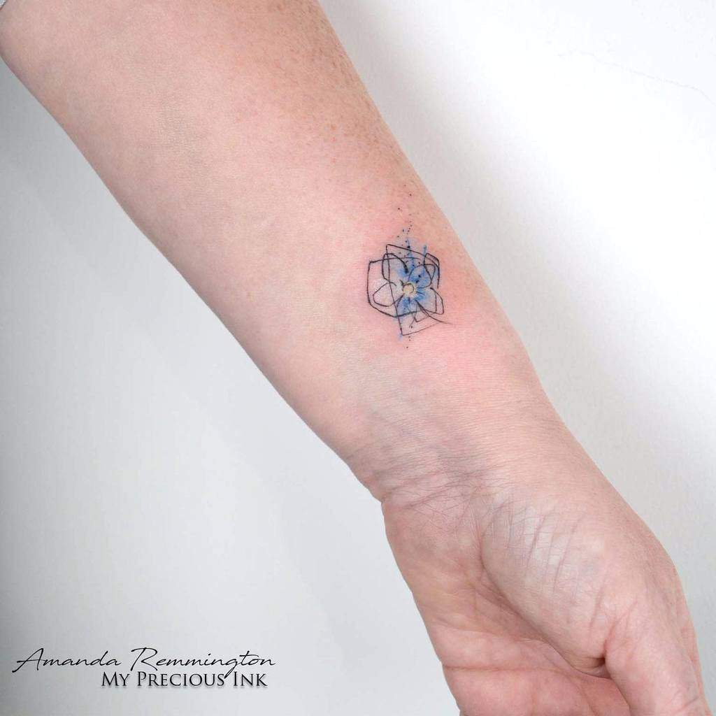 A minimal geometric tattoo featuring a delicate forget-me-not flower inked in blue graces the forearm
