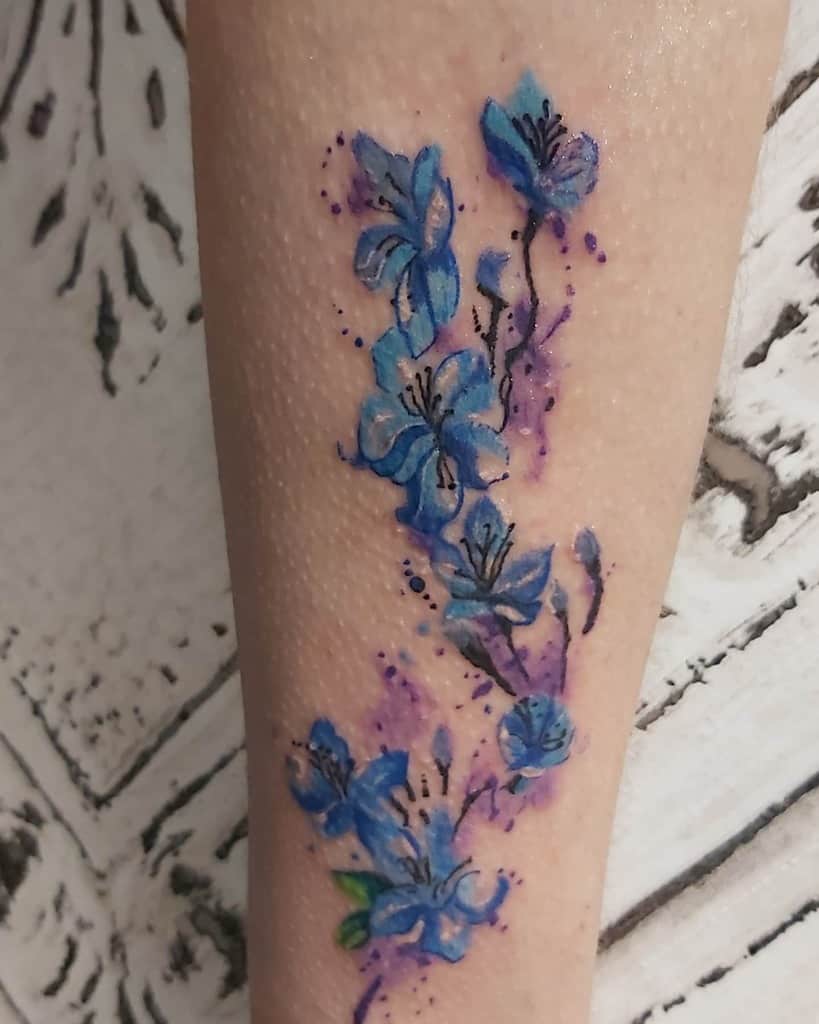 Watercolor forget-me-not flowers in shades of blue and purple, elegantly splashed for a delicate, artistic forearm tattoo