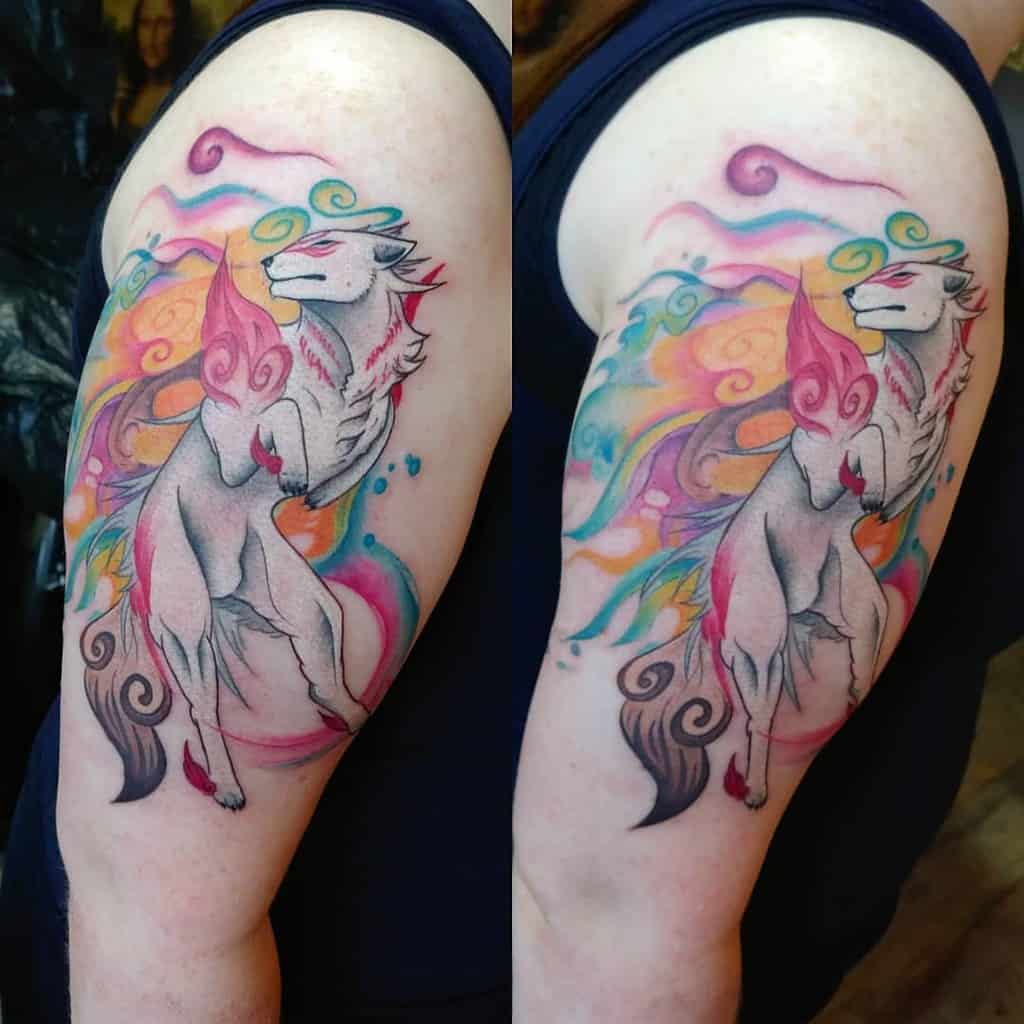 Watercolor-style tattoo on upper arm featuring a Japanese wolf with flowing, multicolored flames and swirling patterns