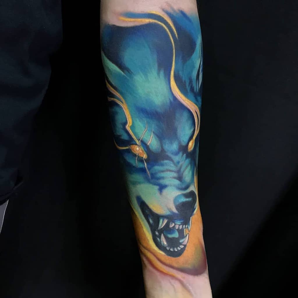 Vibrant tattoo of a snarling wolf with glowing eyes and colorful fur on an arm
