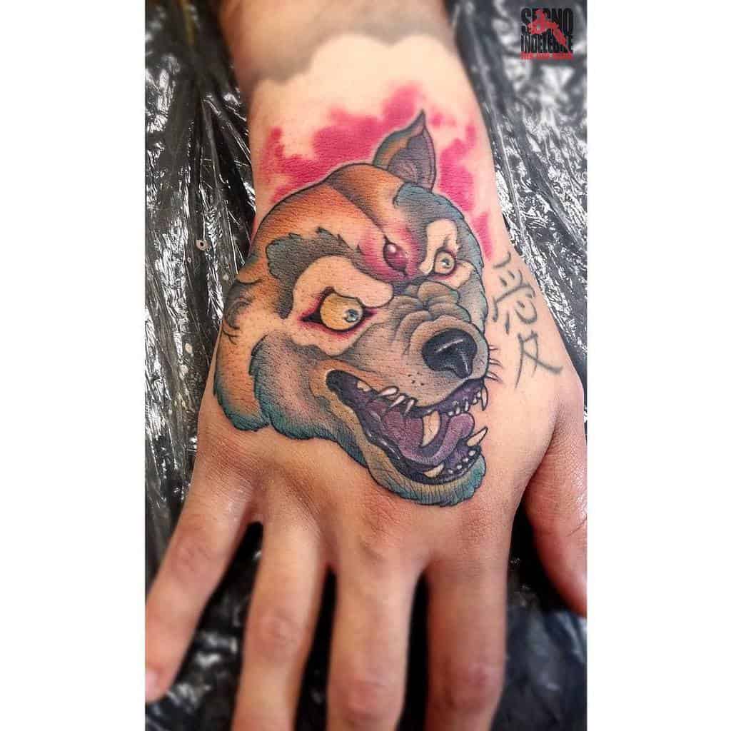 Colorful tattoo of a snarling wolf on a hand, with a red background and runes on the side
