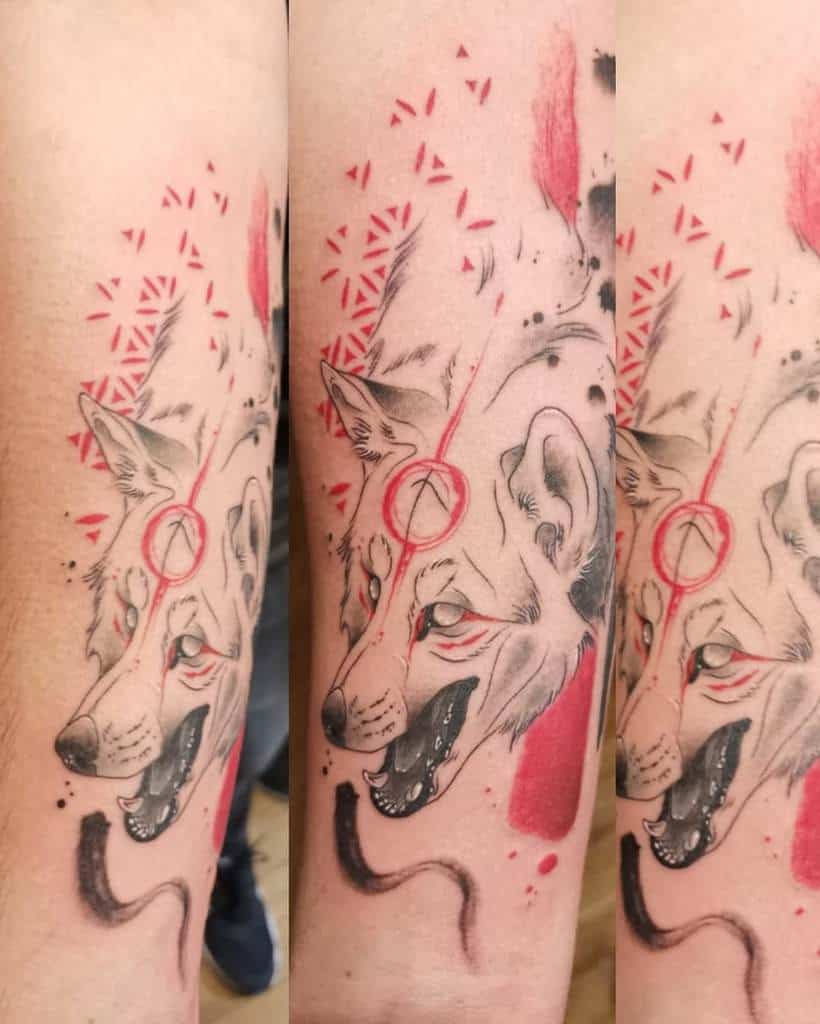 Tattoo of a stylized wolf with red geometric patterns and a circular symbol on its forehead