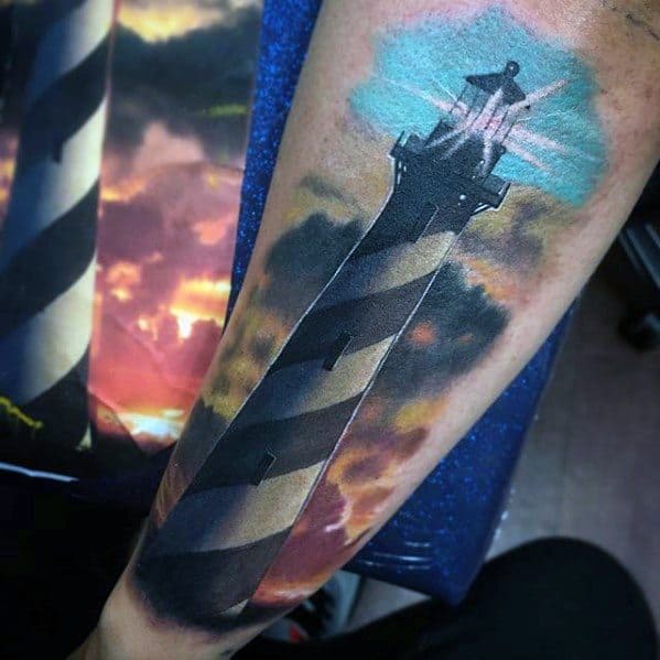 Detailed lighthouse tattoo against a vibrant sky on a person's forearm