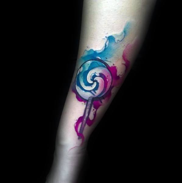 Watercolor-style lollipop tattoo with vibrant swirls of blue and pink, blending soft brushstroke effects with bold outlines for a dynamic design.