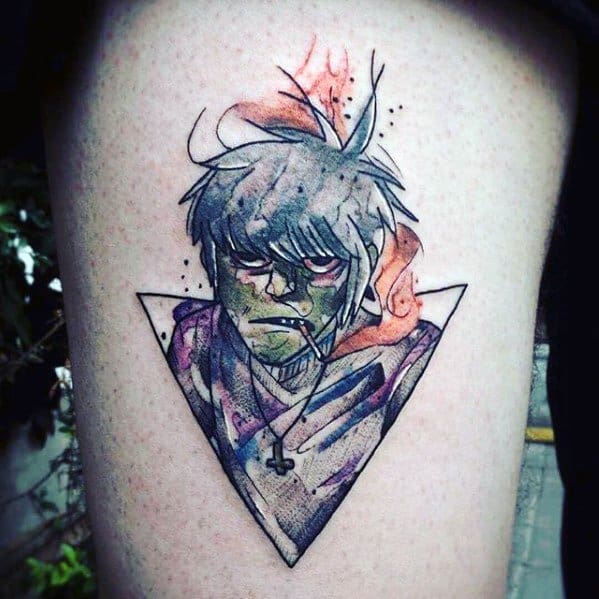 Watercolor-style tattoo of Murdoc from Gorillaz with green skin, messy hair, a cross necklace, and vibrant splashes of orange and purple inside a triangle frame.