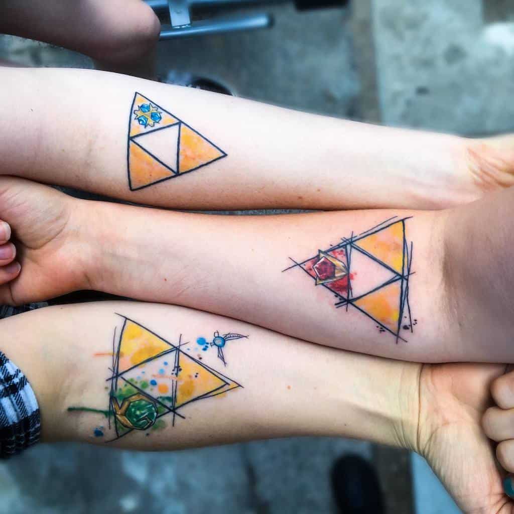 Matching sibling tattoos featuring the Triforce symbol from The Legend of Zelda, each with unique watercolor elements representing different attributes