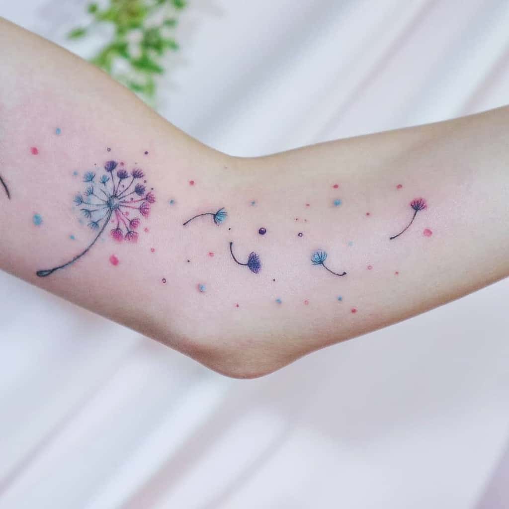 A delicate dandelion tattoo with colorful seeds floating, symbolizing the beauty of change and freedom.