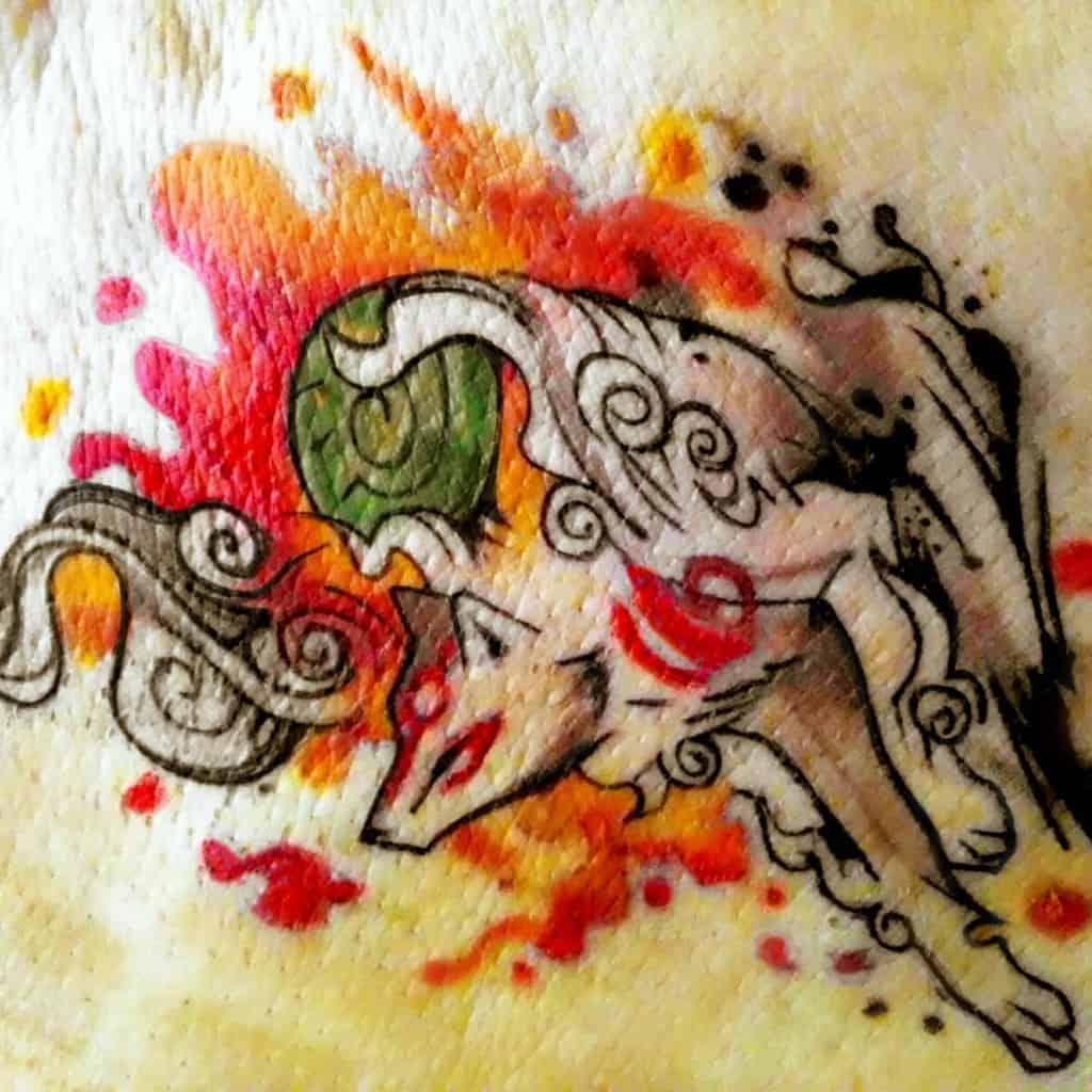 Vibrant watercolor Okami tattoo of Amaterasu with fiery red, orange, and black splashes, capturing the essence of divine energy