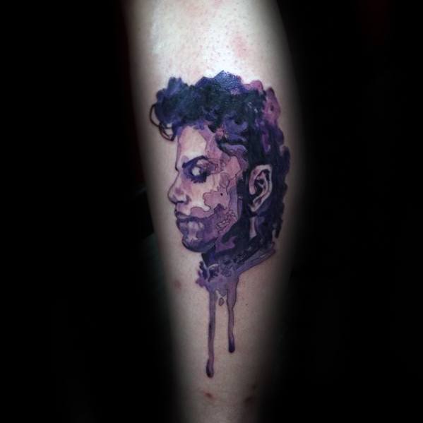 A purple-toned tattoo of Prince's face with artistic drips graces the leg